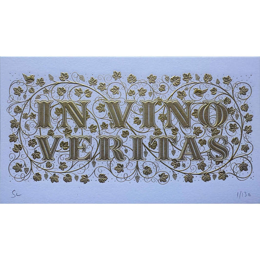 Die stamped print by Seb Lester showing the text In Vino Veritas in fancy lettering and typeface with flourishes and swirls in gold ink on white frost paper. Close up detail.