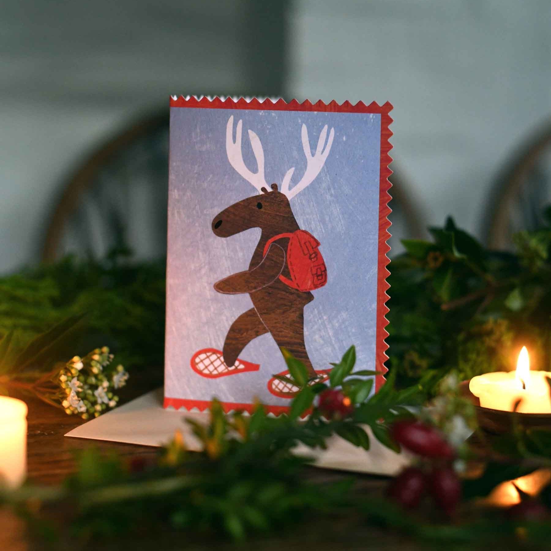 Moose or deer wearing snowshoes and a backpack christmas holiday greeting card by mortlake papers