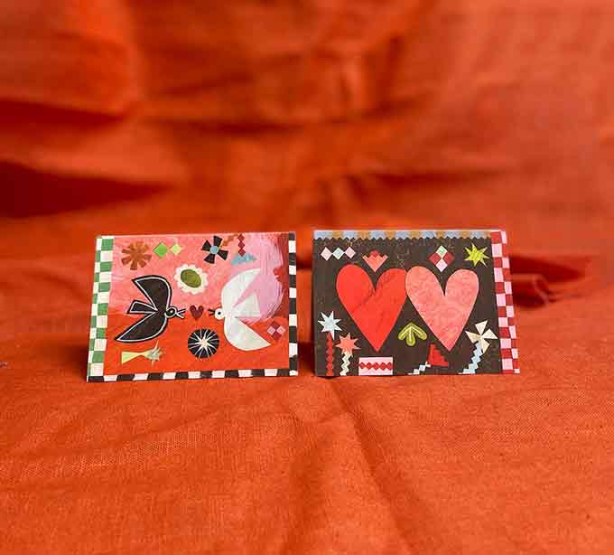 Two valentines cards by Mortlake papers, Birdsong and Two Hearts, on an orange fabric background.