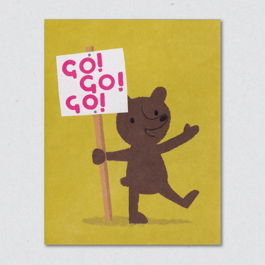 Banner Bear greeting card depicting a cartoon bear holding a 'GO! GO! GO!' sign on a yellow background by Lisa Jones Studio.
