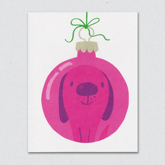 Beagle Bauble Christmas card by Lisa Jones Studio illustrating a pink Christmas tree ornamental bauble with a beagle dog reflection and with a green bow at the top, on a white background.