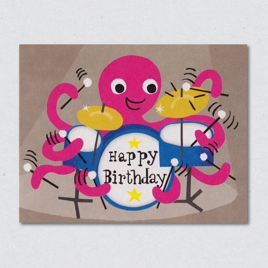 Colorful birthday card with a pink octopus with a blue drumkit with the words 'happy birthday' on a brown background by Lisa Jones Studio.