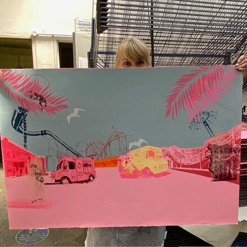 Anna Marrow holding a large colorful original screen printed illustration of a cityscape with palm trees and various elements titled 'Hold on to your hats and enjoy the ride'.