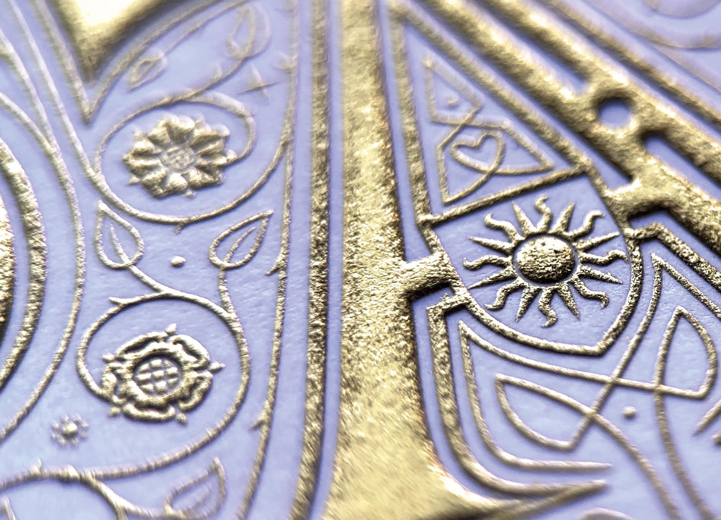 Pax print by Seb Lester. Die stamp with raised impression. Illustrates the word PAX with flourishes and swirls in gold on white. Close up