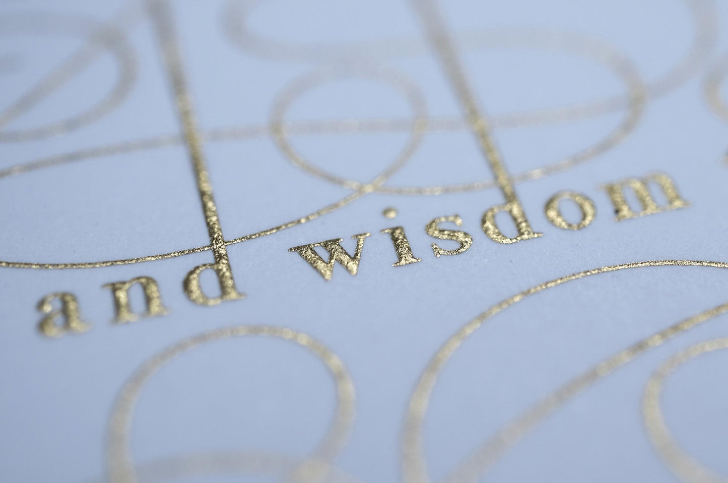 The serenity prayer die stamp print by Seb Lester in gold on white. Features text: "god grant me the serenity to accept the things I cannot change, courage to change the things I can and wisdom to know the different. Type in ornate font and flourishes and swirls around the text. Close up detail.