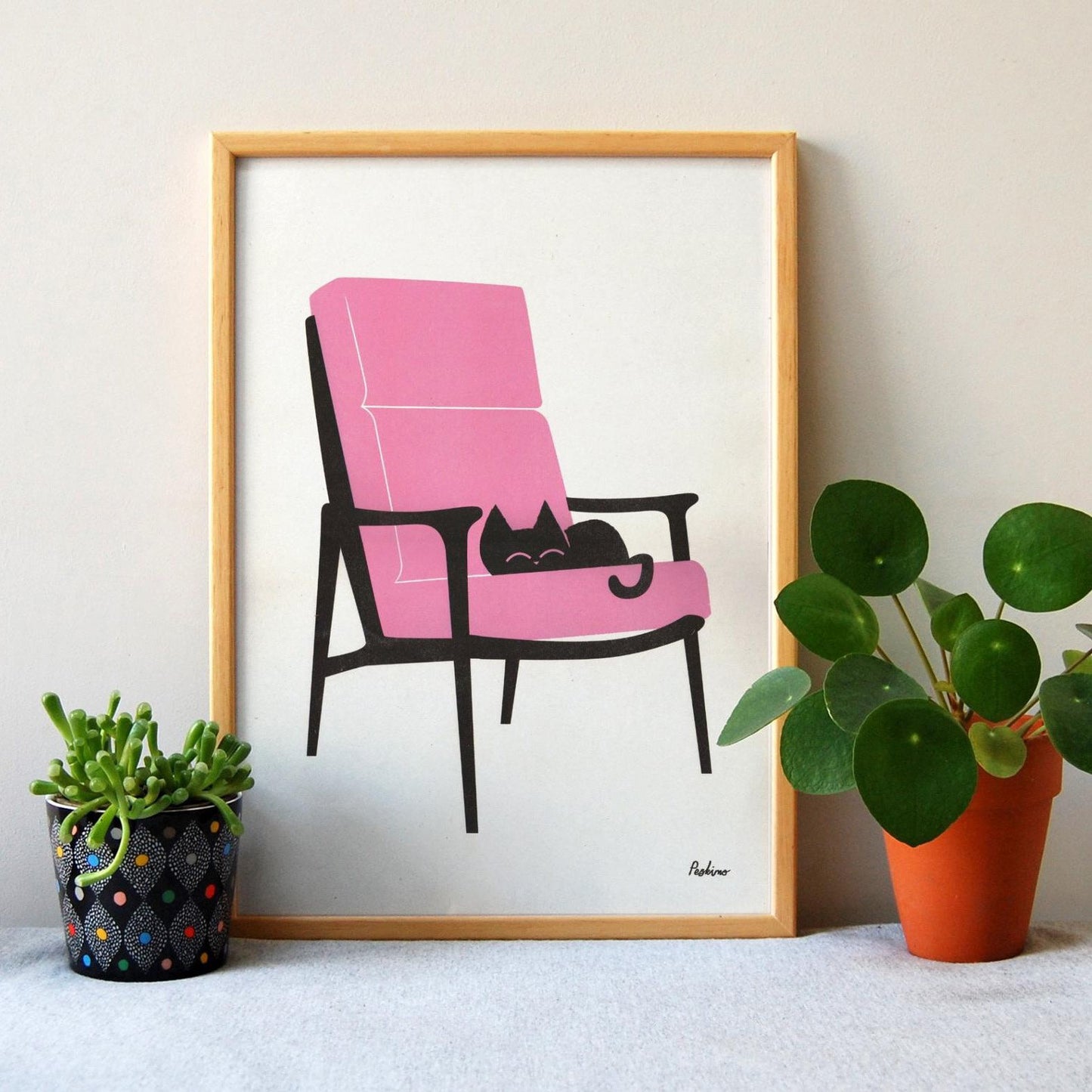 'Cat Nap Armchair' risograph print on recycled paper by Peskimo featuring a black cat on a pink Armchair.