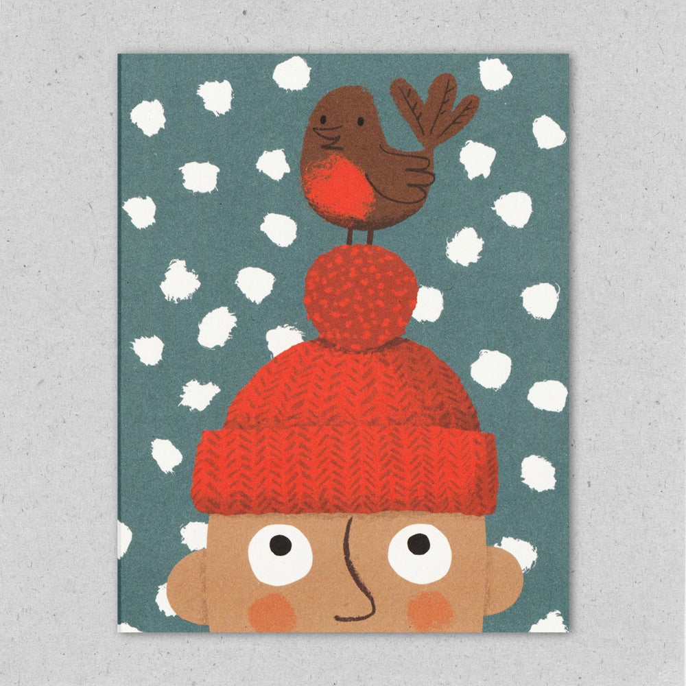A Christmas greeting card featuring an illustration of a robin perched on a bobble hat, with snowflakes in the background by Lisa Jones Studio.