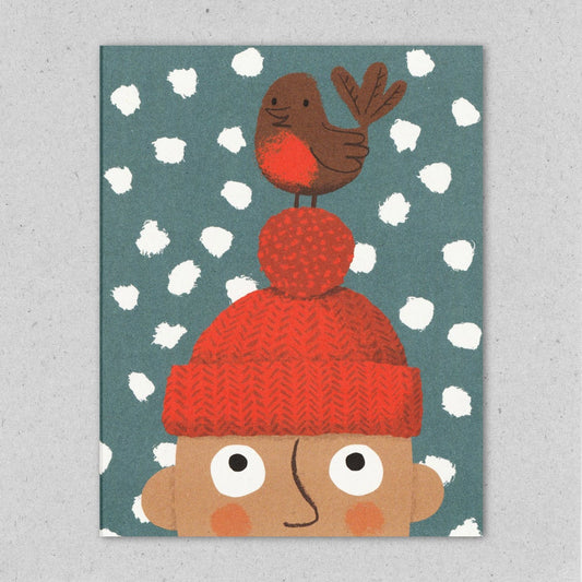 A Christmas greeting card featuring an illustration of a robin perched on a bobble hat, with snowflakes in the background by Lisa Jones Studio.