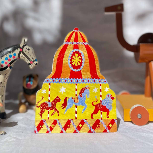 Carousel greeting card by Alice Lickens featuring a greeting card in a fairground carousel style in orange and red with a horse, a lion and a leopard on a shelf with toys.