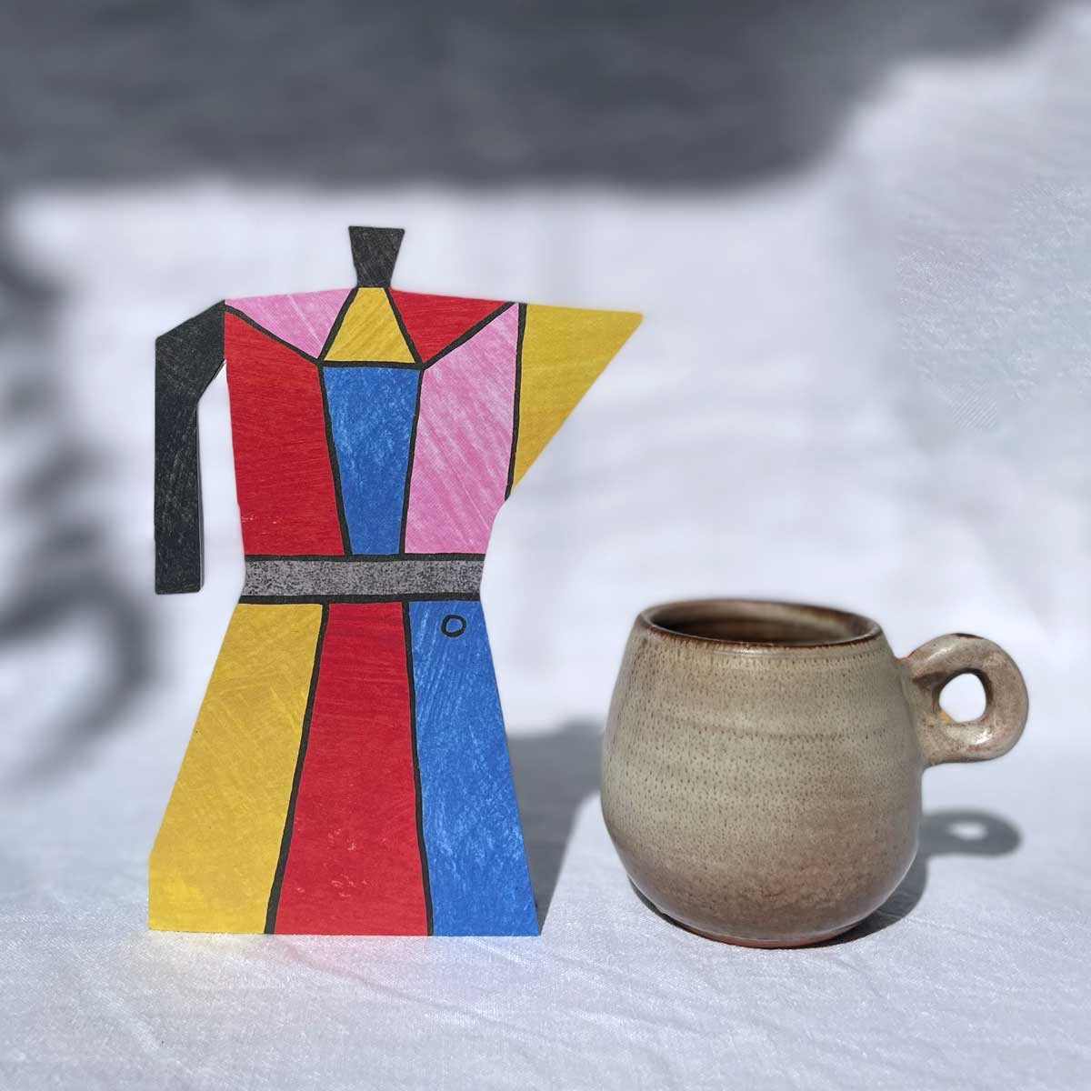 Colour Block Coffee Pot by Mortlake Papers colourful greeting card next to a mug on a grey background.