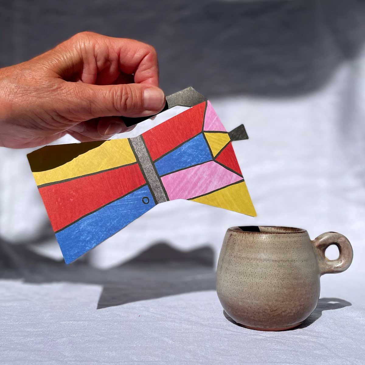 Colour Block Coffee Pot by Mortlake Papers greeting card posed over a mug being poured with a hand as if it was a real moka pot.