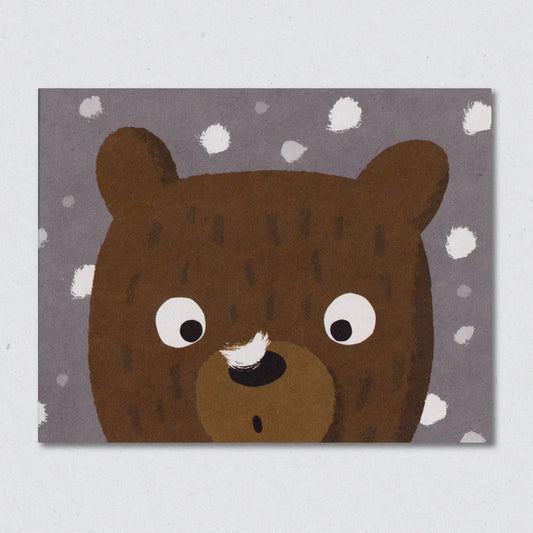 Snowflake Bear Christmas card by Lisa Jones Studio illustrating a cartoon bear face on a gray background with white snow falling and a snowflake on its nose.